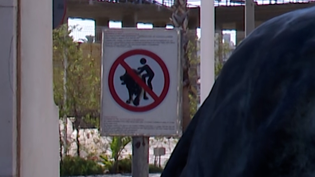 Un cartel intenta evitar que los visitantes se suban encima de los leones del Puerto de Málaga para echarse una foto